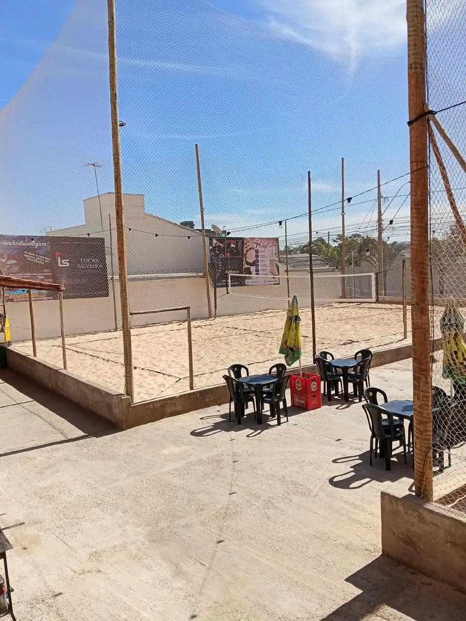 Vista das quadras de areia durante o dia, com mesas na área ao lado